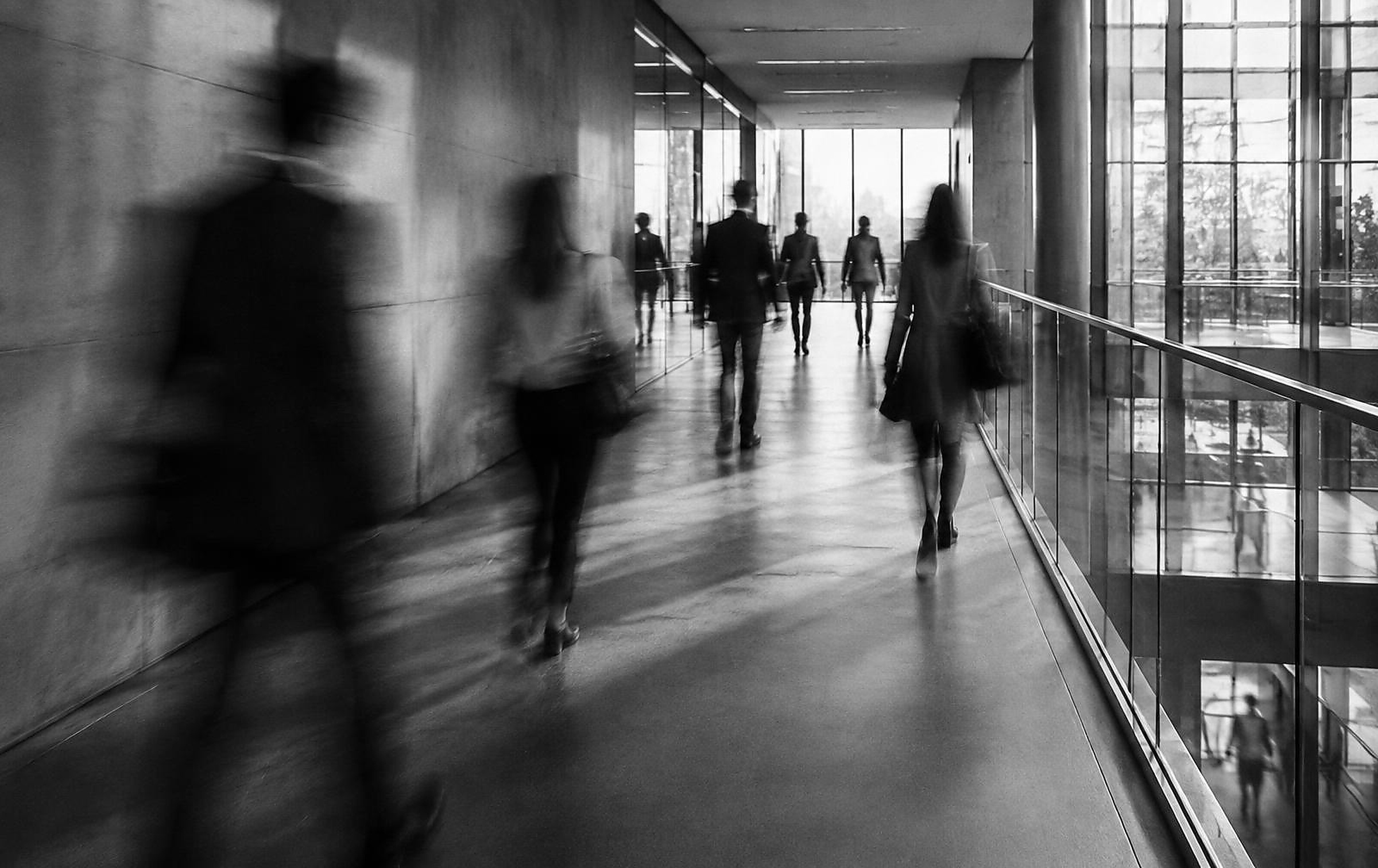 Abstract black and white photograph of people moving through an architectural corridor