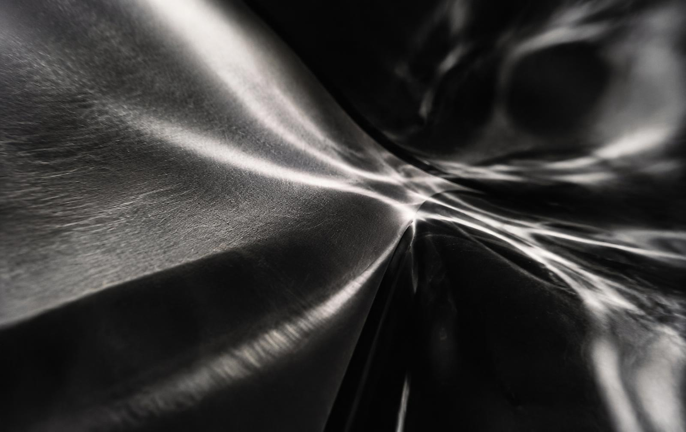 Abstract black and white photograph of light moving across brushed metal and dark glass