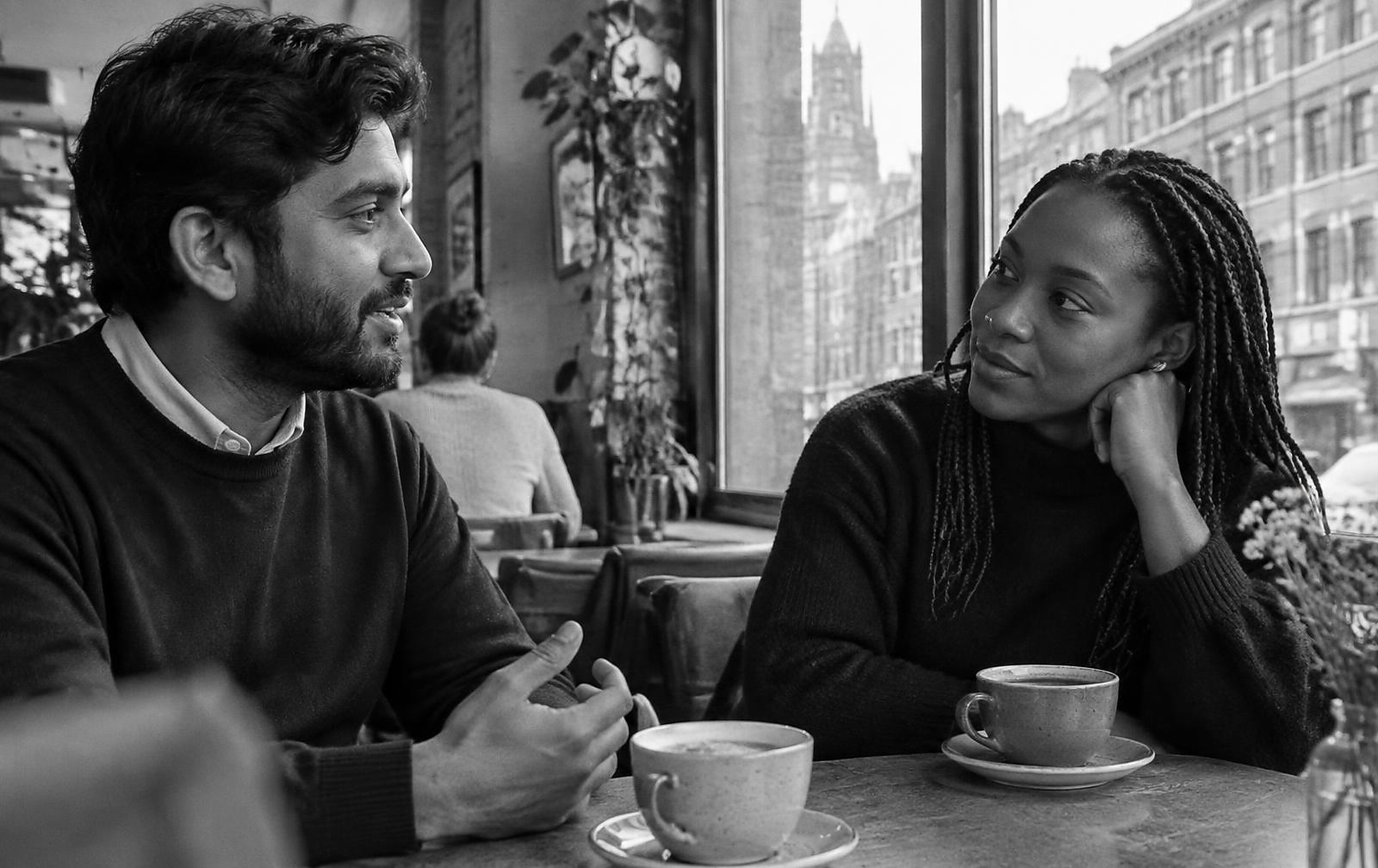Black and white photograph of a relaxed interview conversation across a studio table