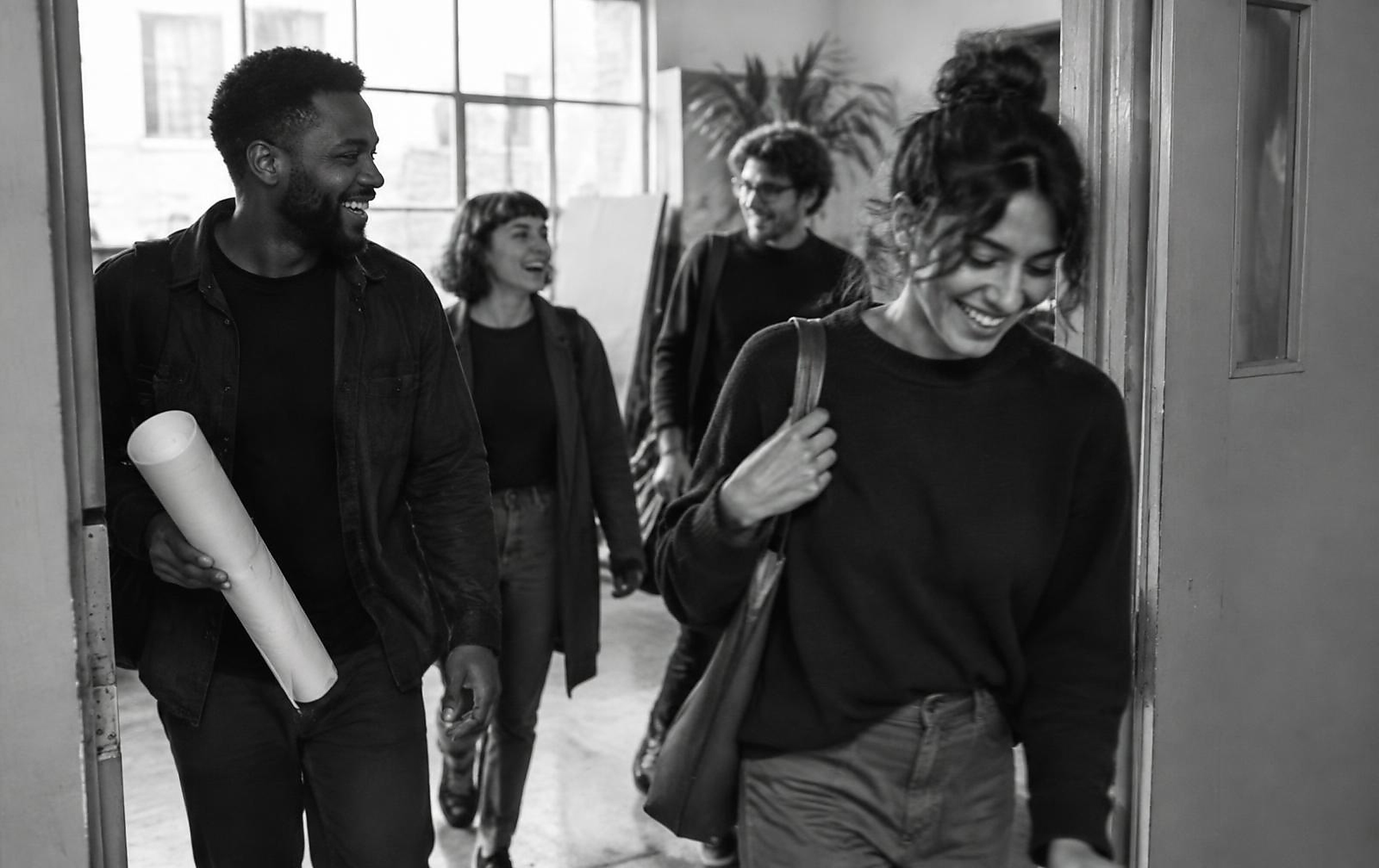 Black and white photograph of a creative team reviewing a wall of notes in a studio